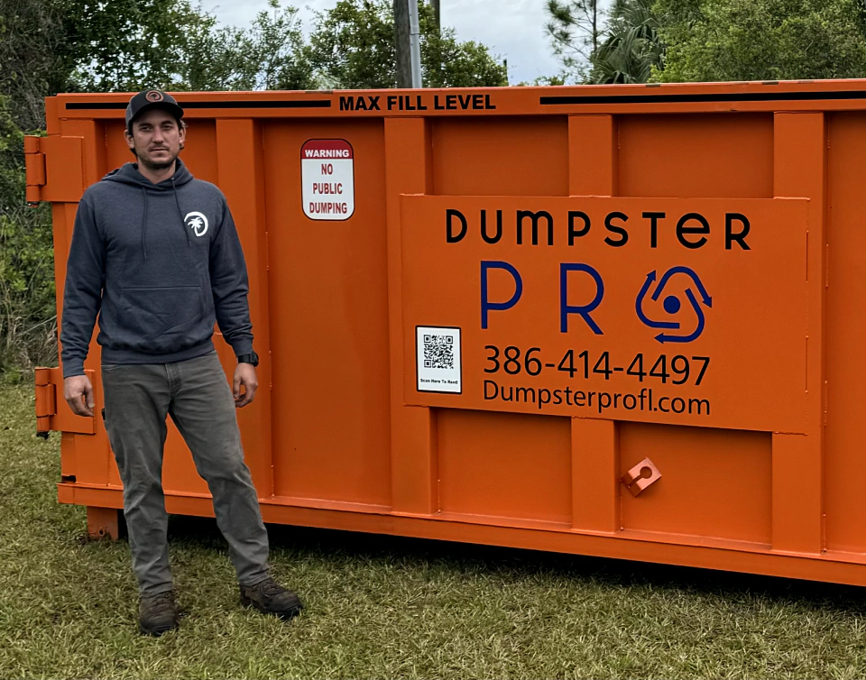 worker on front of an orange dumpster